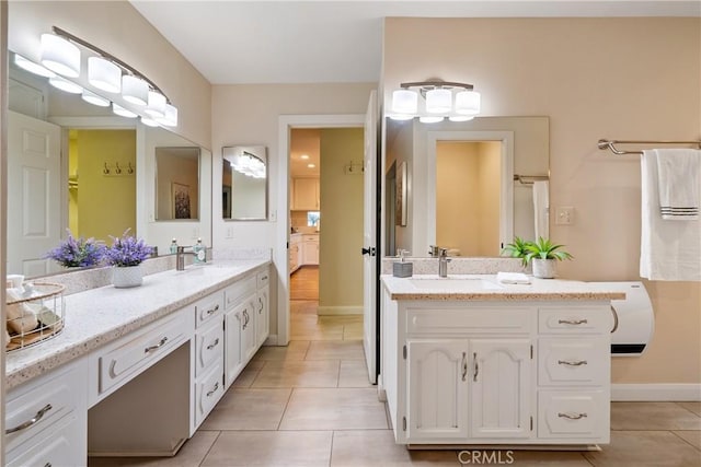 bathroom featuring a sink, tile patterned floors, two vanities, and baseboards
