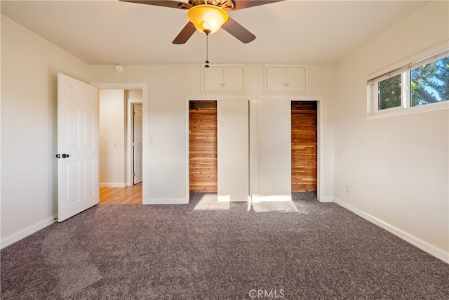 unfurnished bedroom featuring wooden walls, carpet, a closet, and ceiling fan