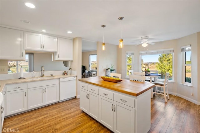 kitchen with light wood-style floors, white cabinets, a sink, white dishwasher, and butcher block countertops