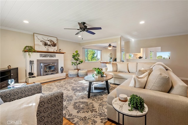 living room with ceiling fan, a fireplace, crown molding, and wood-type flooring