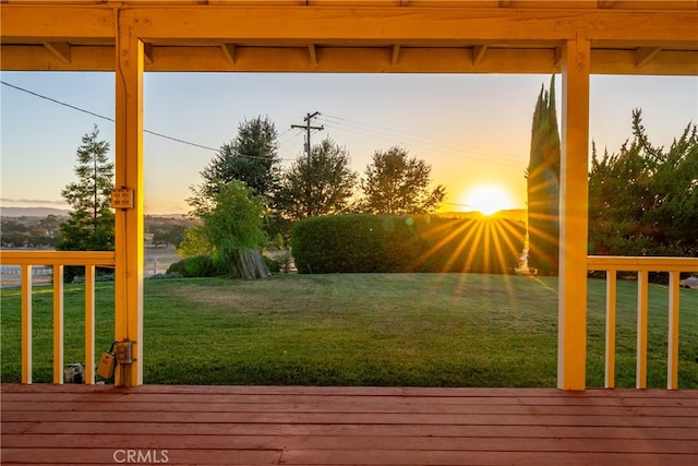 deck at dusk featuring a yard