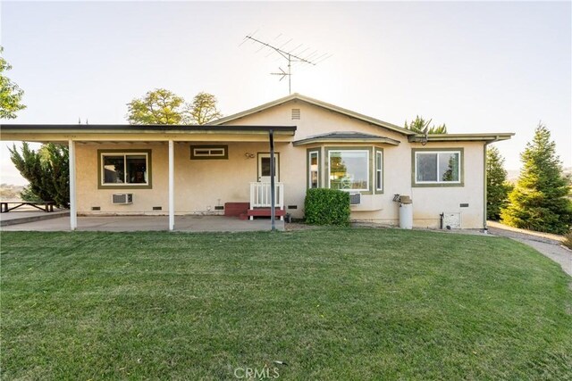back of property featuring a wall mounted AC, a patio, stucco siding, crawl space, and a lawn