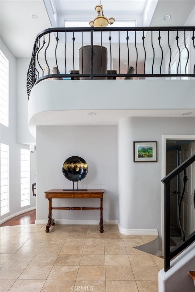 staircase with a towering ceiling, a chandelier, and tile patterned floors