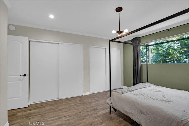 bedroom featuring recessed lighting, two closets, and wood finished floors