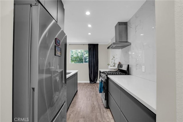 kitchen featuring light countertops, wall chimney exhaust hood, modern cabinets, and stainless steel appliances