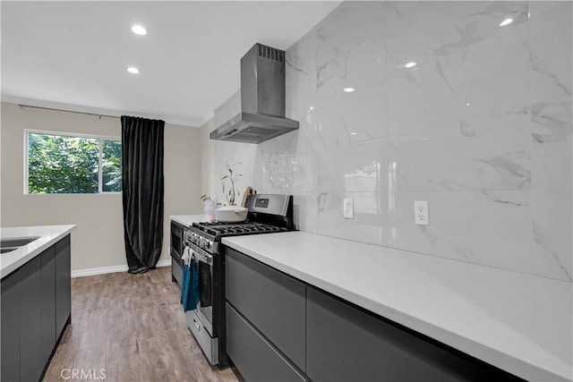 kitchen featuring gray cabinets, gas stove, modern cabinets, and wall chimney range hood