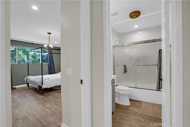 bathroom featuring shower / bath combination with glass door, hardwood / wood-style flooring, and toilet