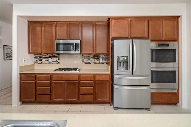 kitchen with backsplash, stainless steel appliances, and light tile patterned flooring