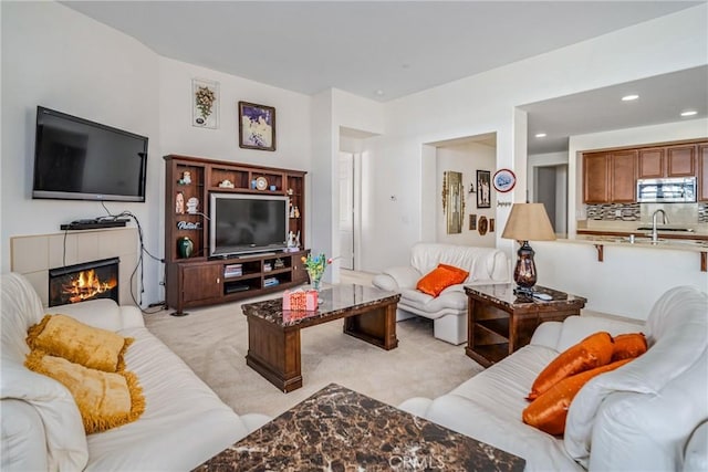 living room featuring sink, light colored carpet, and a fireplace