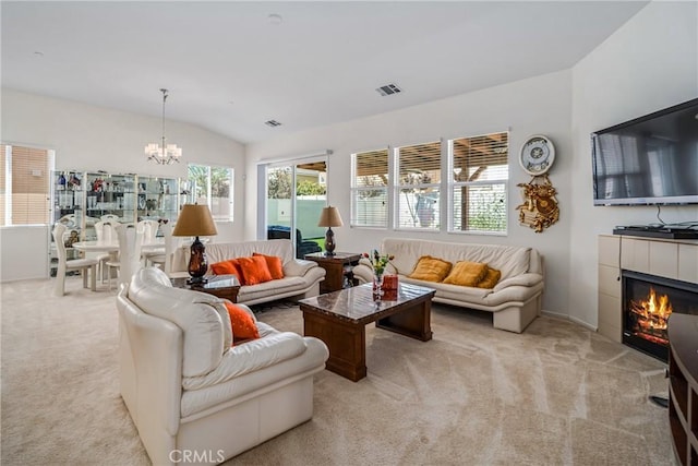 living room featuring an inviting chandelier, light carpet, a tile fireplace, and vaulted ceiling