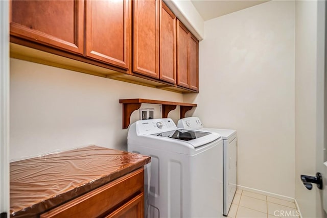 clothes washing area featuring washer and dryer, cabinets, and light tile patterned floors