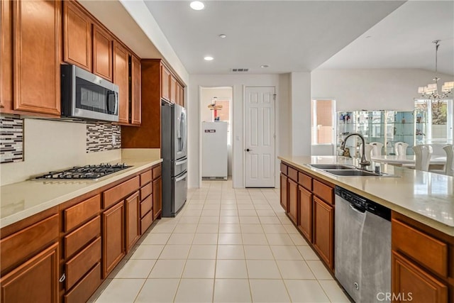 kitchen with sink, hanging light fixtures, tasteful backsplash, stainless steel appliances, and a chandelier