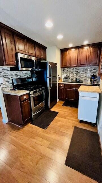 kitchen with stainless steel appliances, backsplash, and light hardwood / wood-style floors