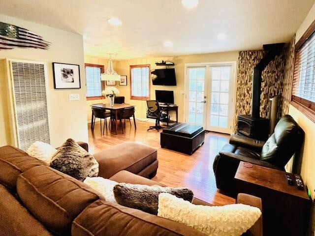 living room with french doors, light hardwood / wood-style floors, and a wood stove