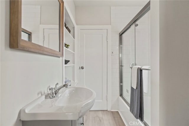 bathroom with wood-type flooring and enclosed tub / shower combo