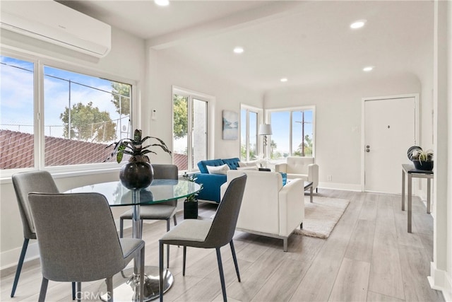 dining room with a wall mounted AC and light wood-type flooring