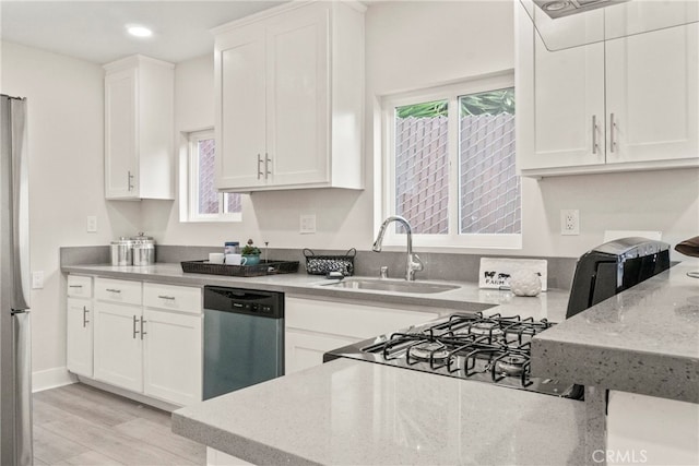 kitchen featuring light wood-type flooring, sink, stainless steel appliances, light stone countertops, and white cabinetry