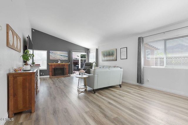 living room with a fireplace, lofted ceiling, and light hardwood / wood-style flooring