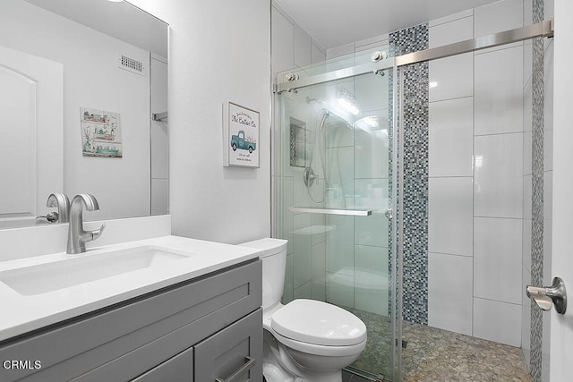 bathroom featuring vanity, toilet, and a shower with door