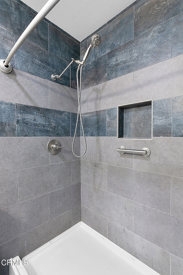 bathroom with a textured ceiling and tiled shower