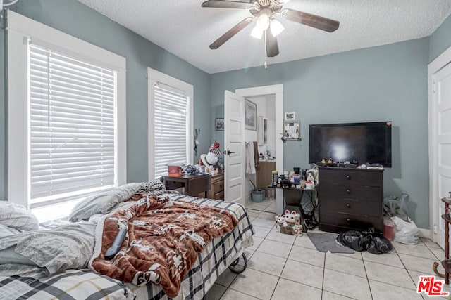 tiled bedroom with ceiling fan and a textured ceiling