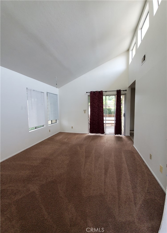 carpeted empty room with high vaulted ceiling