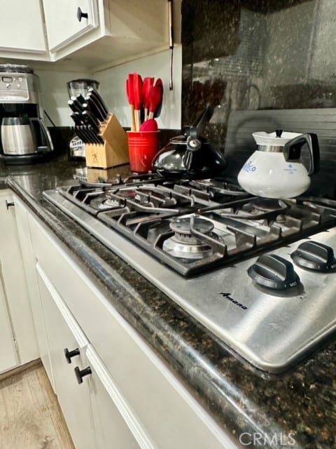 interior details with stainless steel gas cooktop, hardwood / wood-style floors, and white cabinets