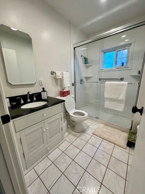 bathroom featuring tile patterned flooring, a shower with shower door, vanity, and toilet