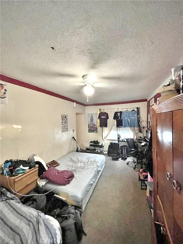 bedroom featuring carpet, a textured ceiling, ceiling fan, and ornamental molding