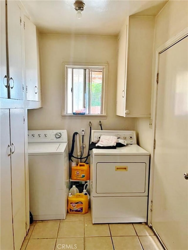 washroom featuring light tile patterned flooring, cabinets, and washing machine and clothes dryer