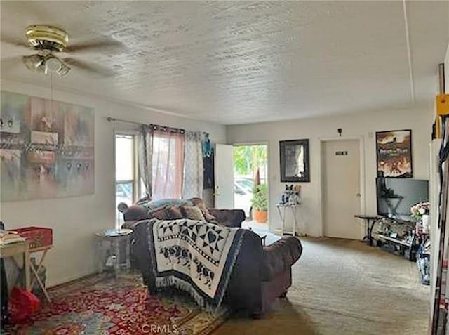 carpeted living room featuring ceiling fan and a textured ceiling