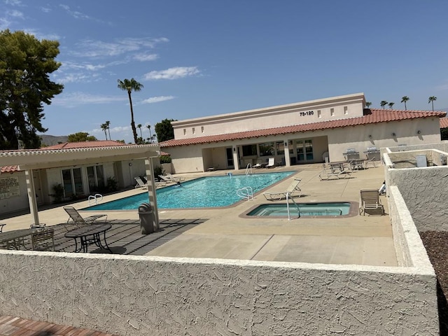 view of swimming pool featuring a hot tub and a patio area