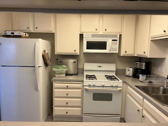 kitchen featuring white appliances, white cabinetry, and sink