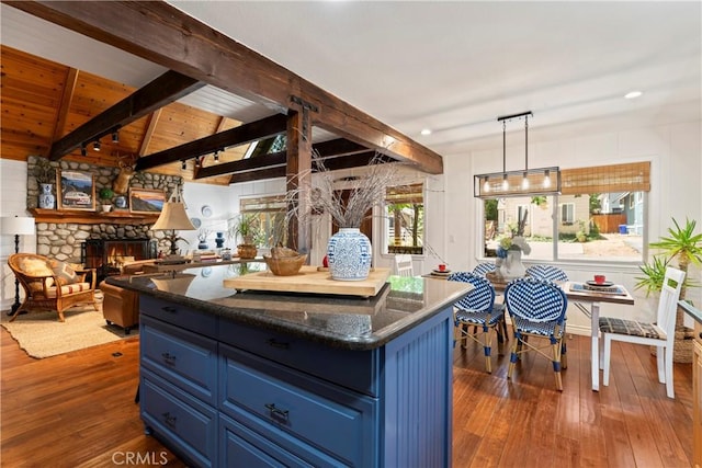 kitchen with a fireplace, lofted ceiling with beams, hanging light fixtures, blue cabinetry, and wooden ceiling