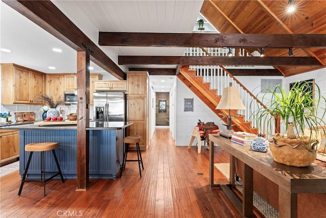 kitchen with appliances with stainless steel finishes, a kitchen bar, beamed ceiling, dark hardwood / wood-style floors, and wooden ceiling