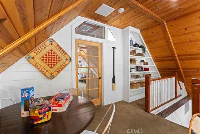 dining room featuring built in shelves, wood walls, vaulted ceiling, wooden ceiling, and dark carpet