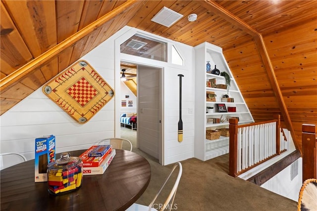 interior space with carpet floors, vaulted ceiling, wooden walls, built in shelves, and wooden ceiling