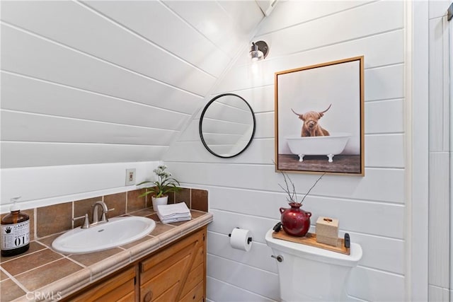 bathroom featuring toilet, vanity, and lofted ceiling