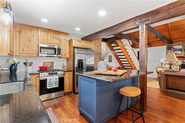 kitchen featuring stainless steel appliances, decorative light fixtures, dark hardwood / wood-style flooring, light brown cabinetry, and a breakfast bar