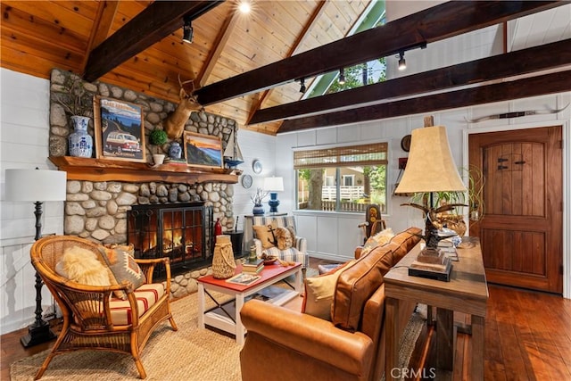 sitting room with lofted ceiling with beams, wood ceiling, wooden walls, and a stone fireplace