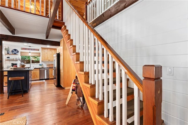 stairs featuring beam ceiling and hardwood / wood-style flooring