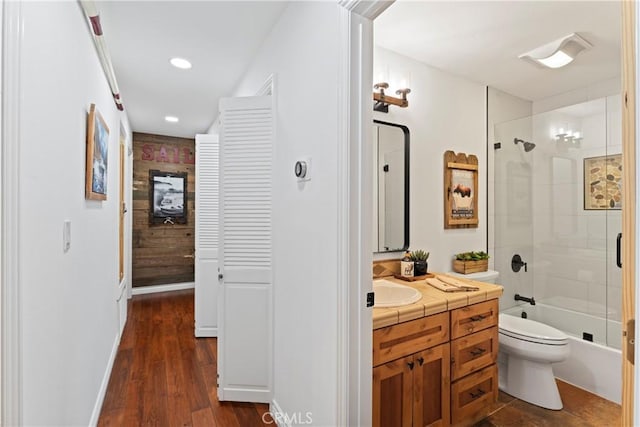 full bathroom featuring toilet, enclosed tub / shower combo, hardwood / wood-style floors, and vanity