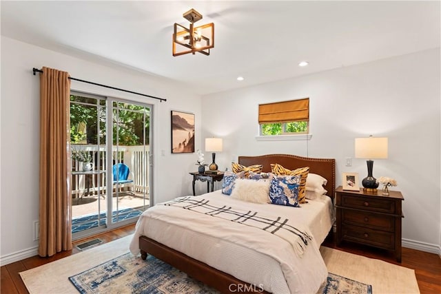 bedroom with hardwood / wood-style floors, access to outside, and an inviting chandelier