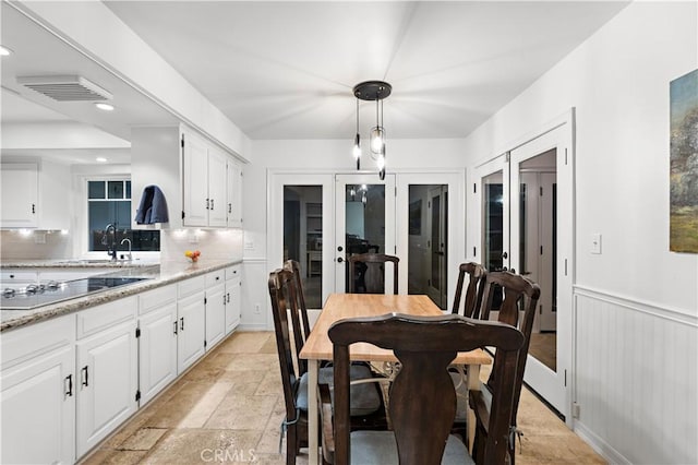 dining space with recessed lighting, stone tile floors, visible vents, french doors, and wainscoting