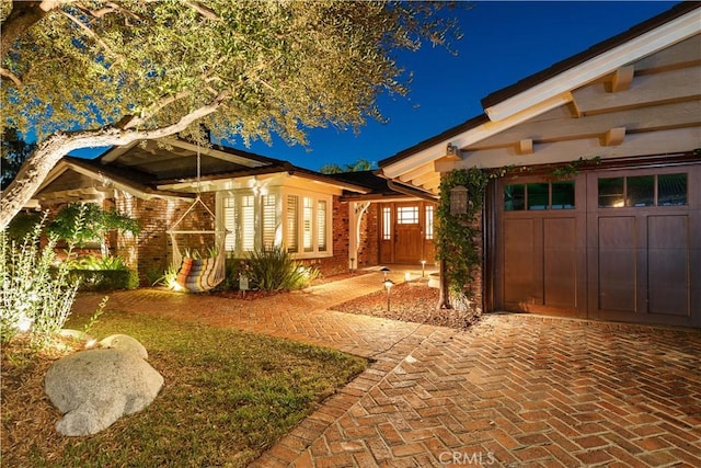 view of property exterior with decorative driveway and an attached garage