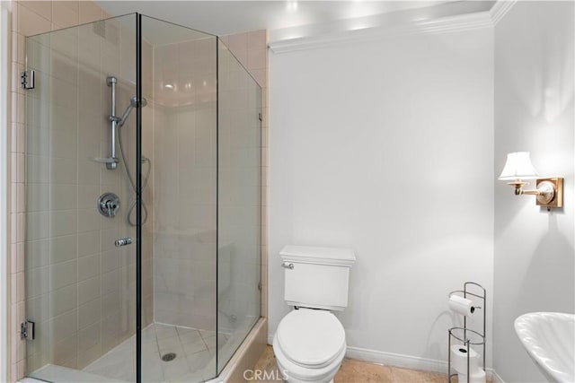 bathroom with a stall shower, baseboards, toilet, tile patterned floors, and crown molding