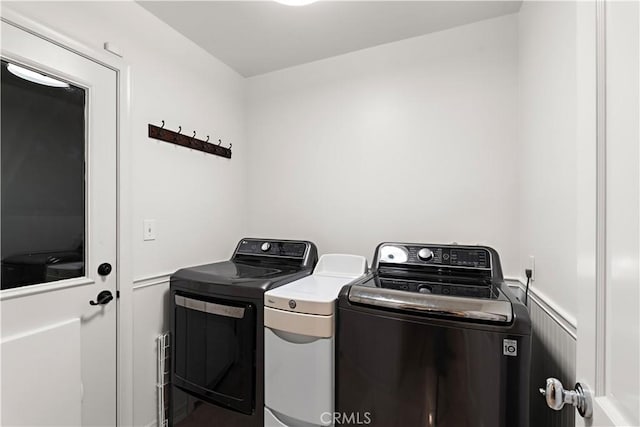 washroom featuring a wainscoted wall, laundry area, independent washer and dryer, and a decorative wall