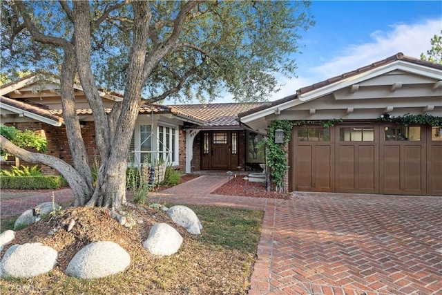 view of front of house featuring a tiled roof, decorative driveway, and an attached garage