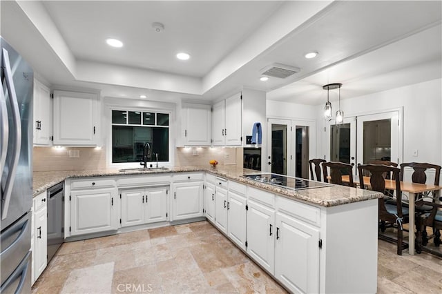 kitchen with a peninsula, appliances with stainless steel finishes, a sink, and decorative backsplash