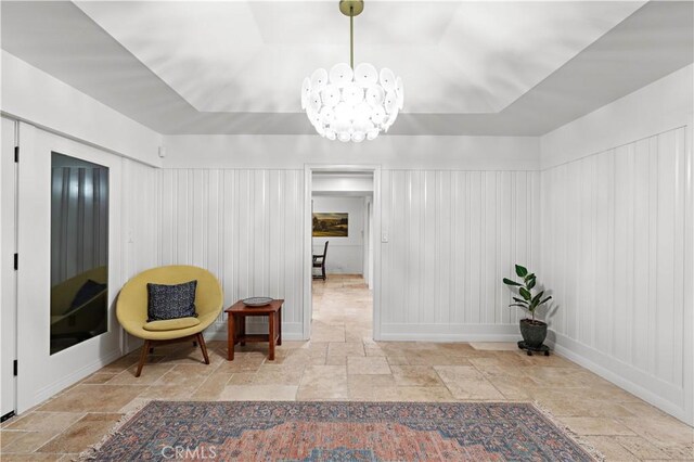 living area featuring a notable chandelier and a raised ceiling